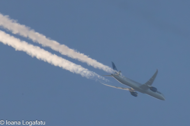 Airplane soaring high with white trails in the sky